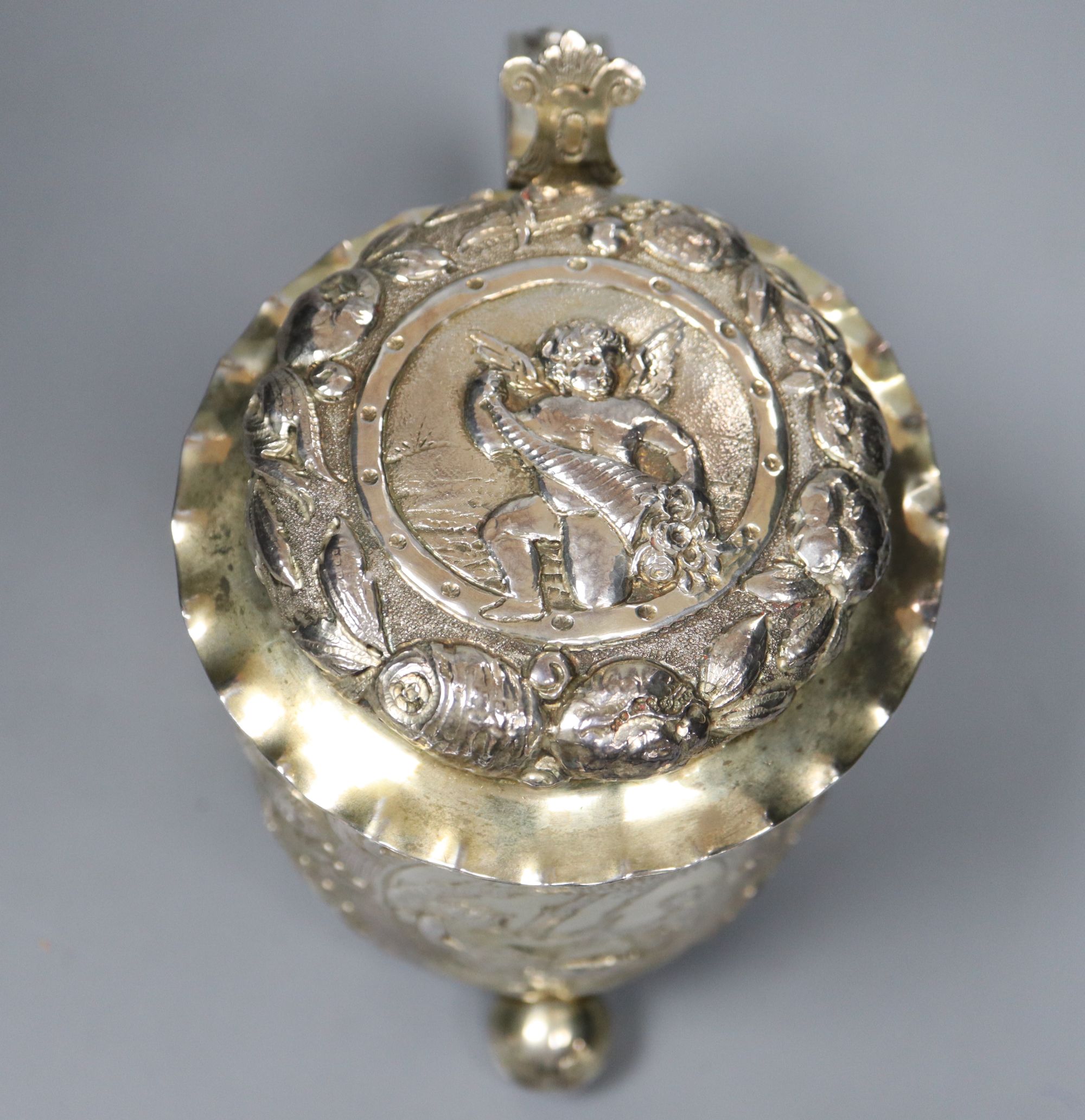 A late 19th century German? silver Scandinavian style embossed lidded tankard, on three ball feet,